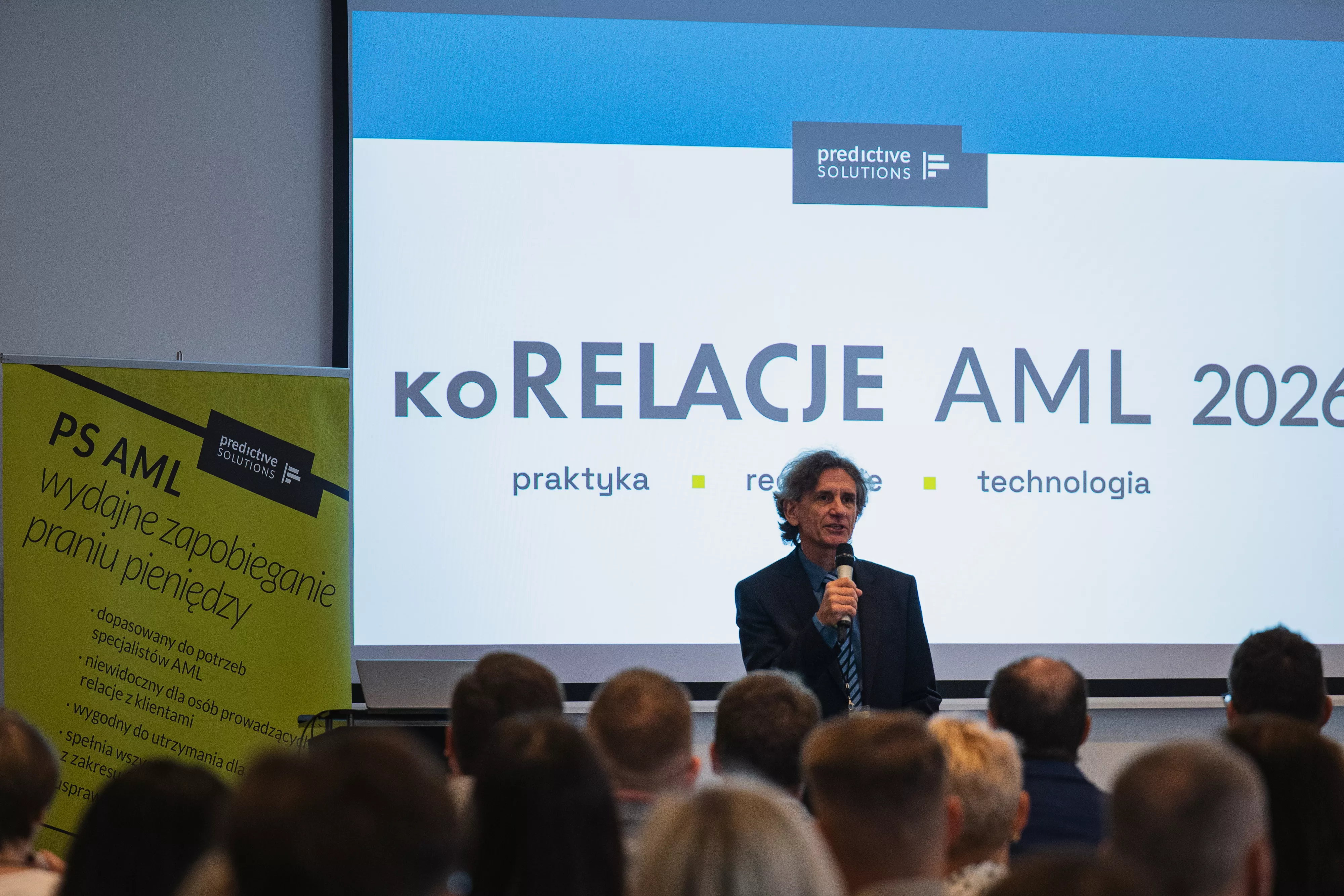 Zdjęcie przedstawia prezesa Predictive Solutions przemawiającego na tle prezentacji koRELACJE AML